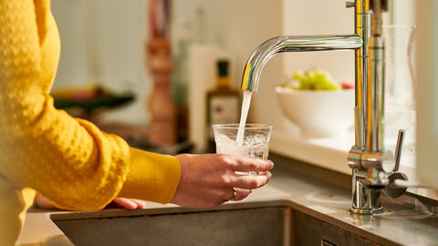 vrouw vult glas water in de keuken