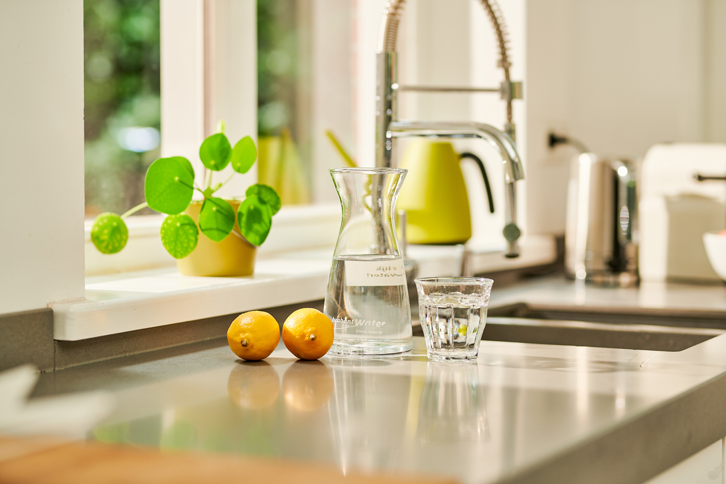 karaf en glas water met citroen in keuken