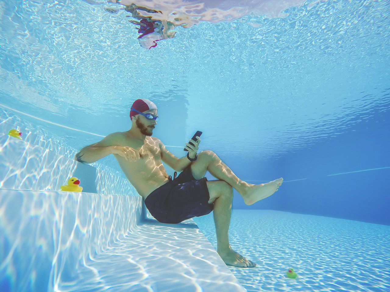 Man onder water kijkt op zijn telefoon