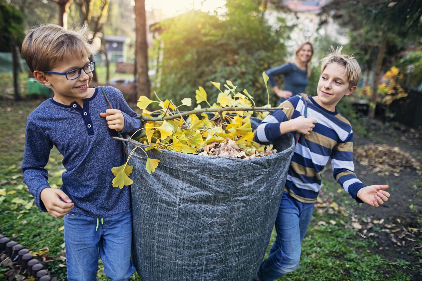 kinderen ruimen afgevallen bladeren in tuin op