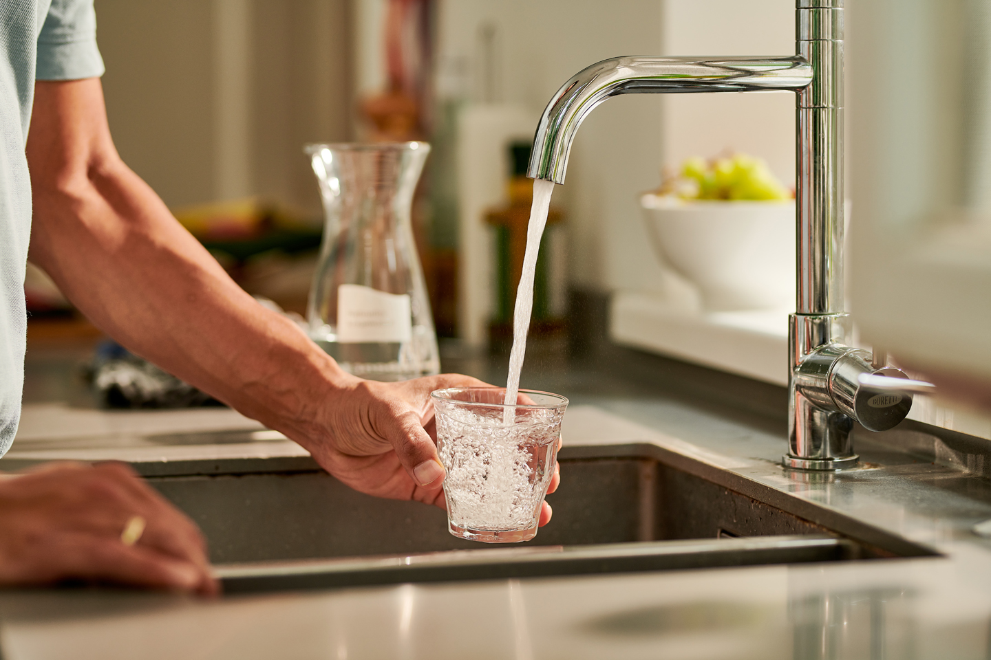 Man vult glas water in keuken