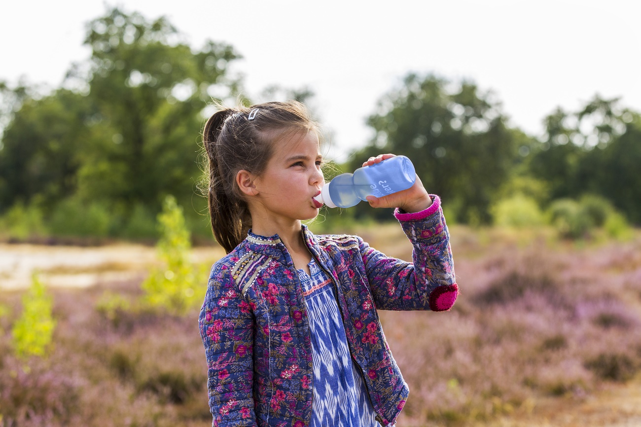 Meisje met bidon buiten in natuur