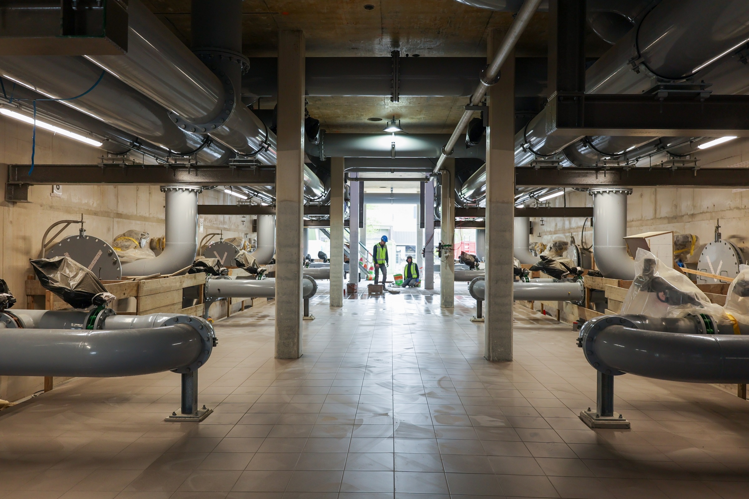 Mannen aan het werk en buizen in nieuwbouw zuiveringsgebouw