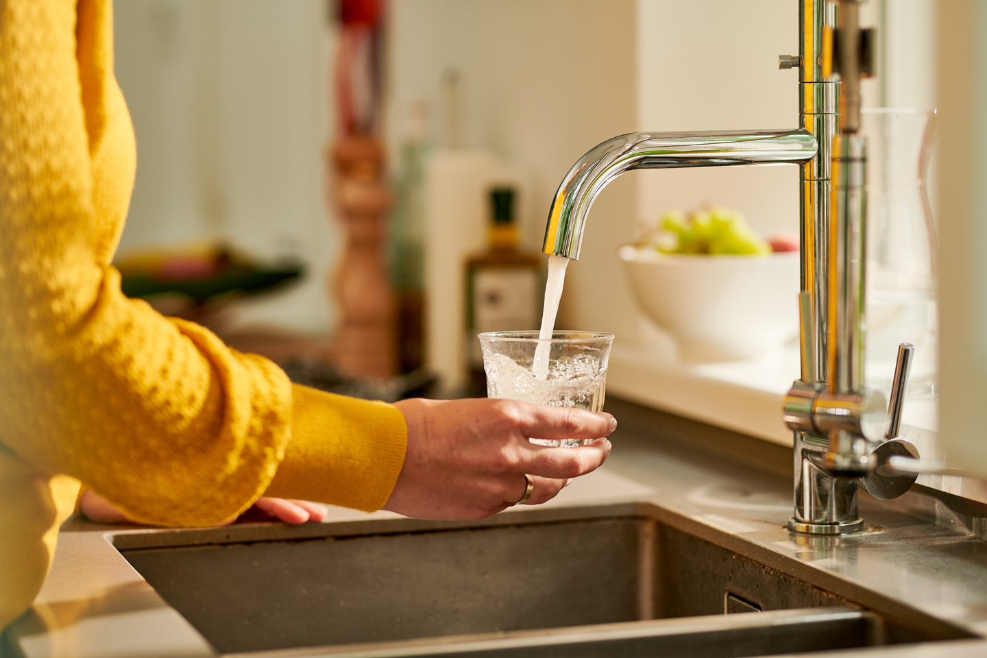 vrouw vult glas water in de keuken