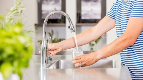 Vrouw vult glas met kraanwater
