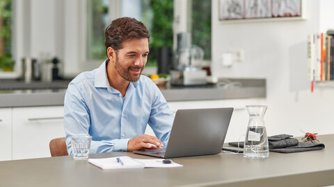 Man aan tafel achter laptop