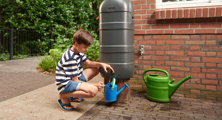 jongen vult gieter uit regenton
