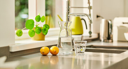 karaf en glas water met citroen in keuken
