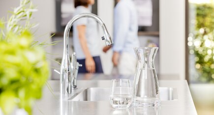 karaf en glas water op aanrecht bij keukenkraan