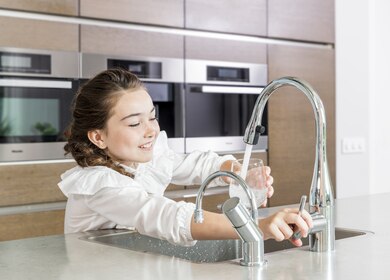 meisje vult glas onder kraan