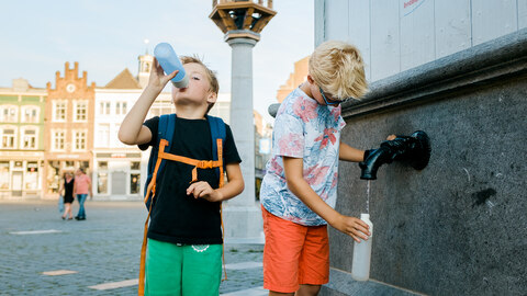 Kinderen tappen water uit watertappunt