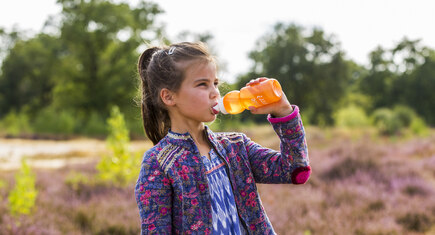 Meisje drinkt uit flesje in de natuur