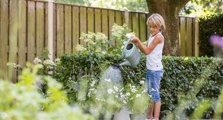 Jongen geeft tuin water met gieter